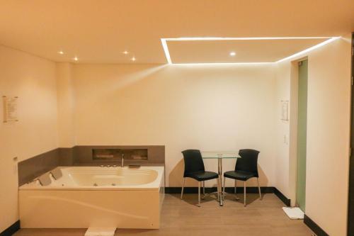 La salle de bains est pourvue d'une baignoire, de 2 chaises et d'une table. dans l'établissement Hotel Loyds, à Medellín