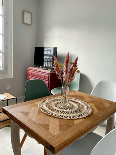 une table de salle à manger avec un vase de fleurs dessus dans l'établissement Les Courlis - app cosy et proche mer Ault, à Ault