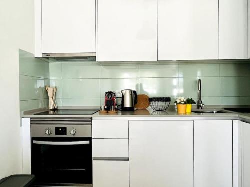 eine Küche mit weißen Schränken und einem schwarzen Backofen in der Unterkunft Casa da Ana - Country Home in Terrugem