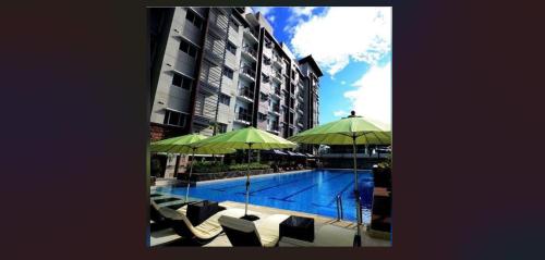 a swimming pool with chairs and umbrellas next to a building at Cozy Suite Studio type condo in Matina Enclaves in Davao City