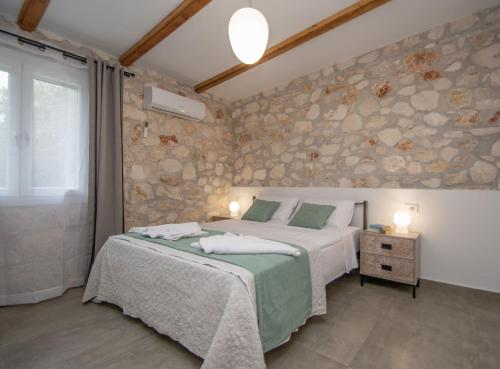 a bedroom with a bed and a stone wall at Green Oak Villa in Orthoniaí