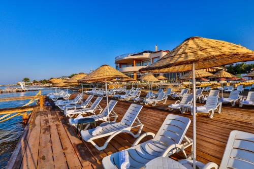 a bunch of lounge chairs and umbrellas on a beach at Club Hotel Gultur in Kucukkuyu