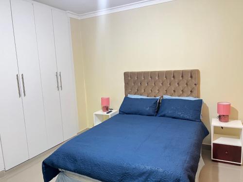 a bedroom with a blue bed and white cabinets at Hibiscus Apartments in Ndola