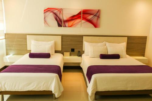 2 letti in una camera d'albergo con dipinti alle pareti di Hotel Loyds a Medellín