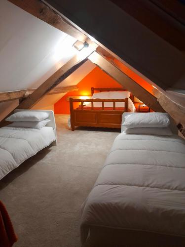 Cette chambre mansardée comprend 4 lits et un mur orange. dans l'établissement Les Roches Chambre d'Hotes, à Servant