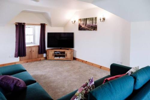a living room with a couch and a flat screen tv at Stockman's Cottage in Kirkcudbright