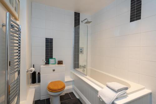 a white bathroom with a toilet and a tub at Spacious 2 bedroom High Street apartment in North Berwick