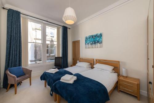 1 Schlafzimmer mit 2 Betten, einem Stuhl und einem Fenster in der Unterkunft Spacious 2 bedroom High Street apartment in North Berwick