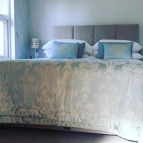 a large bed with blue pillows on top of it at The Lychgate in Caldicot