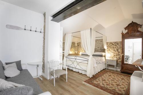 a bedroom with a canopy bed and a couch at GardaBeds Adults Only in Castelnuovo del Garda