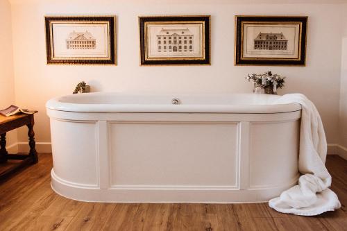 a white bath tub in a room with pictures on the wall at No 24 Beverston Castle in Tetbury