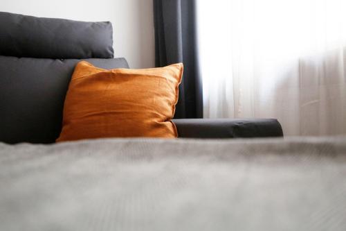 an orange pillow sitting on a bed next to a window at Be in Berlin Apartments im Bergmannkiez in Berlin