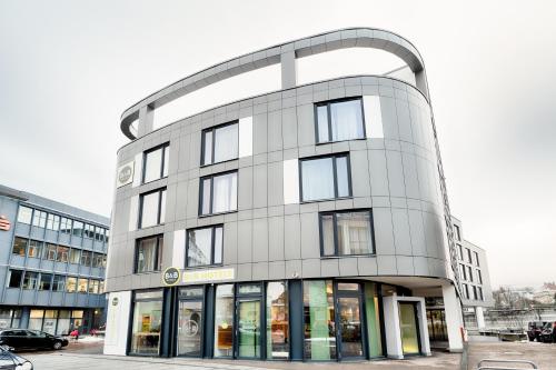 ein großes weißes Gebäude mit gekrümmter Fassade in der Unterkunft B&B Hotel Aalen in Aalen