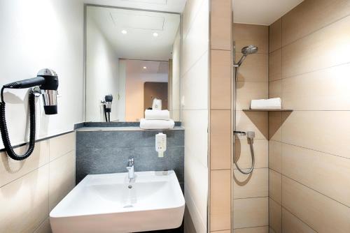 uma casa de banho com um lavatório e um chuveiro em B&B Hotel Augsburg-West em Augsburg