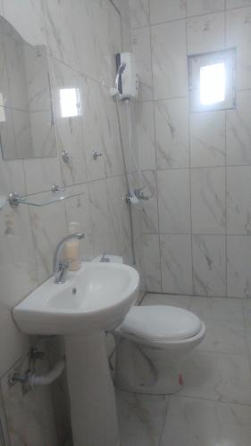 a white bathroom with a toilet and a sink at Çiftlik otel in Çiftlik