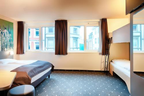 a hotel room with two beds and two windows at B&B Hotel Aachen-City in Aachen
