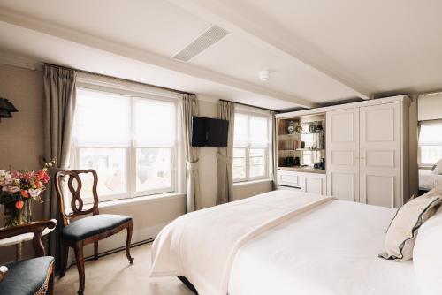 a bedroom with a bed and a chair and windows at Hotel 717 in Amsterdam