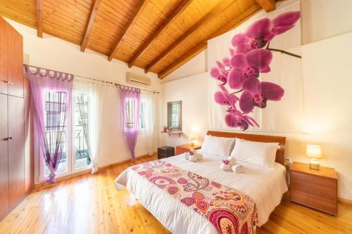 1 dormitorio con 1 cama grande con flores púrpuras en la pared en Minalva Residence, en Mantoúkion