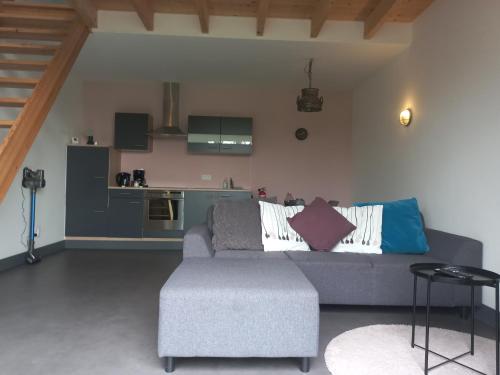 a living room with a couch and a kitchen at Landelijk appartement in een mooi recreatiegebied in Abcoude