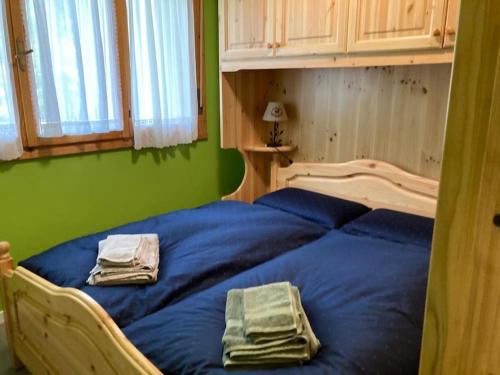 ein Schlafzimmer mit einem blauen Bett und Handtüchern darauf in der Unterkunft Il Nido Dell'Aquila-Piancavallo in Piancavallo