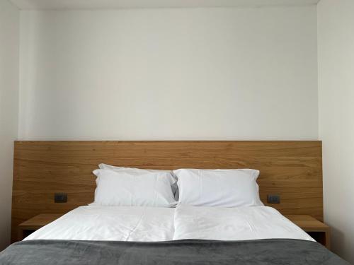 1 cama grande con sábanas y almohadas blancas en Hotel Belvedere en Spiazzi Di Caprino
