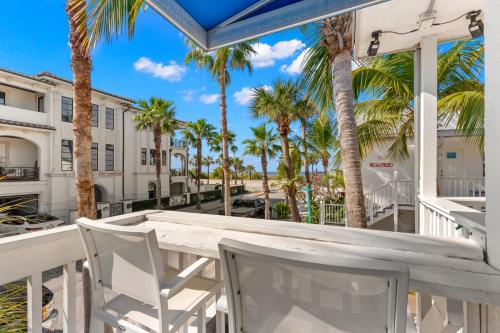 a table and chairs on a balcony with palm trees at Inn on the Beach in St Pete Beach