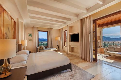 um quarto com uma cama, uma televisão e um sofá em CAP VERMELL GRAND HOTEL em Canyamel