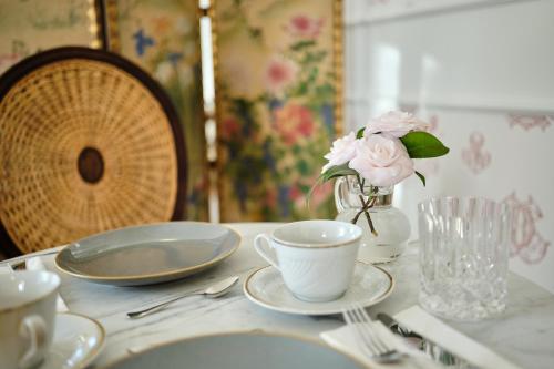 a table with plates and cups and a vase of flowers at HOTEL BOUTIQUE VILLA DEL MARQUÉS in Muros de Nalón