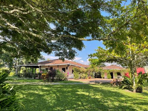 a house with a green yard and trees at MuchoSur Quimbaya in Quimbaya