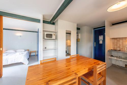 a room with a wooden table and a bed at Résidence les Cavales in Carcans