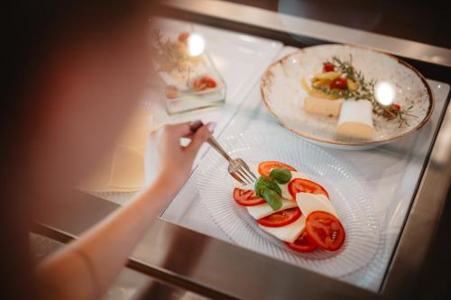 a person holding a fork and a plate of food at Schieners Hotel & Apfelhof Apartments in Wemding