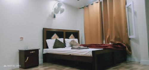 een slaapkamer met een bed met witte lakens en kussens bij Hotel saspolo skardu in Skardu