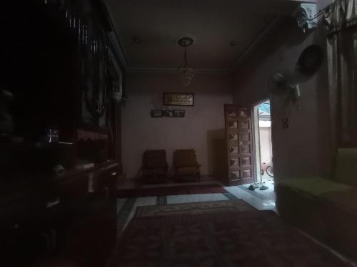a dark room with two chairs and a door at Hossam hotil in Jazīrat al ‘Awwāmīyah
