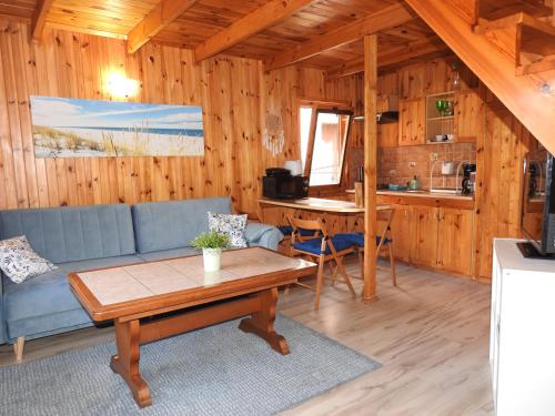 uma sala de estar com um sofá azul e uma mesa em Domki u Skrzata Drewniane em Leba
