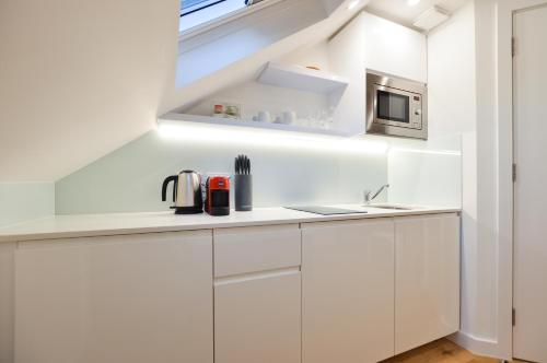 een witte keuken met een wastafel en een magnetron bij West Hampstead Serviced Apartments by Concept Apartments in Londen