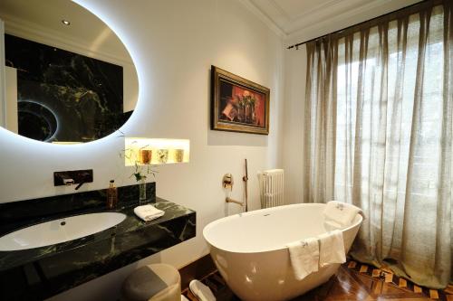 ein Badezimmer mit einer Badewanne, einem Waschbecken und einem Spiegel in der Unterkunft HOTEL BOUTIQUE VILLA DEL MARQUÉS in Muros de Nalón