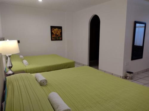 two beds in a room with green sheets and a lamp at Mi Depa Cascada in Ciudad Valles