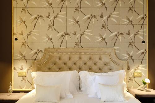 a bed with white pillows and a wall with birds at HOTEL BOUTIQUE VILLA DEL MARQUÉS in Muros de Nalón