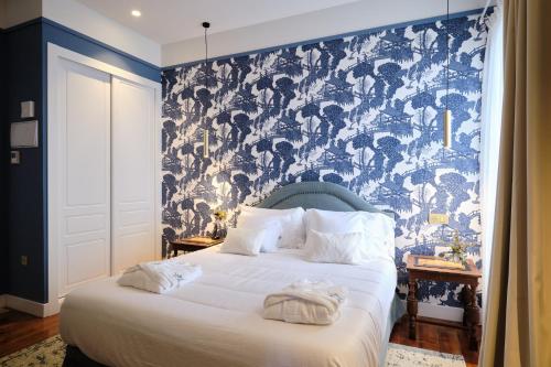 a bedroom with a bed with a blue and white wallpaper at HOTEL BOUTIQUE VILLA DEL MARQUÉS in Muros de Nalón