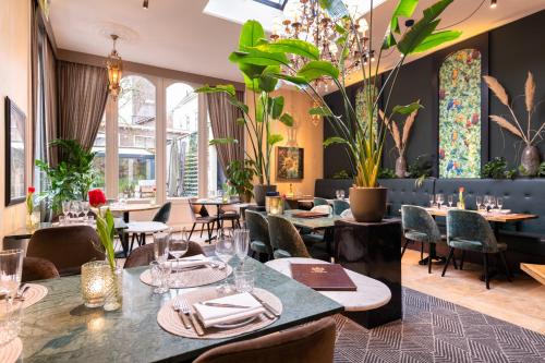 um restaurante com mesas, cadeiras e plantas em Grand Boutique Hotel-Restaurant Huis Vermeer em Deventer