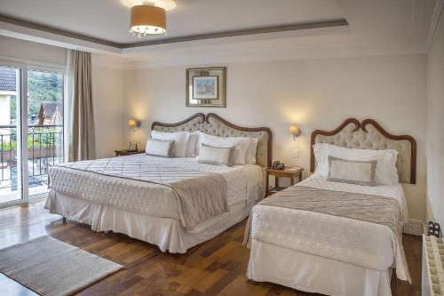 1 dormitorio con 2 camas y balcón en Hotel Estoril en Campos do Jordão