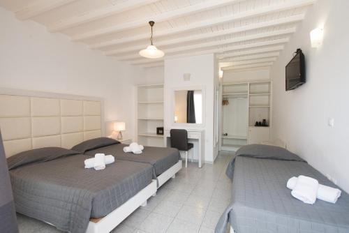 a bedroom with two beds and a desk at Domna Hotel in Mýkonos City