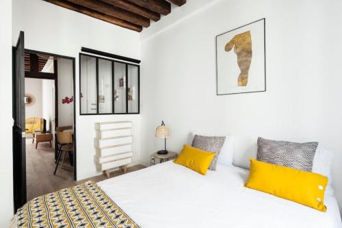 - une chambre avec un grand lit blanc et des oreillers jaunes dans l'établissement Amazing Terrasse in center of Paris, à Paris