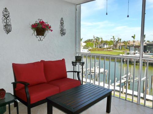 a living room with a red couch and a balcony at Tranquil waterfront condo with pool and steps to beach in Marco Island