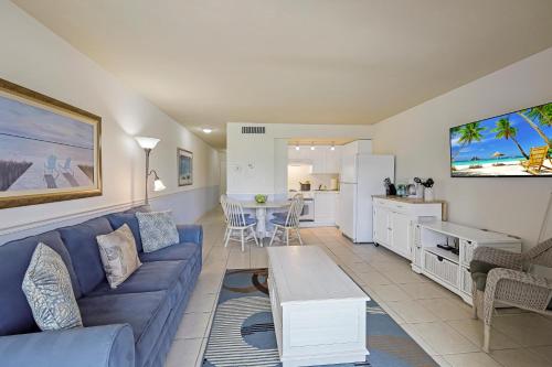 a living room with a blue couch and a kitchen at Beach Club 216 in Marco Island