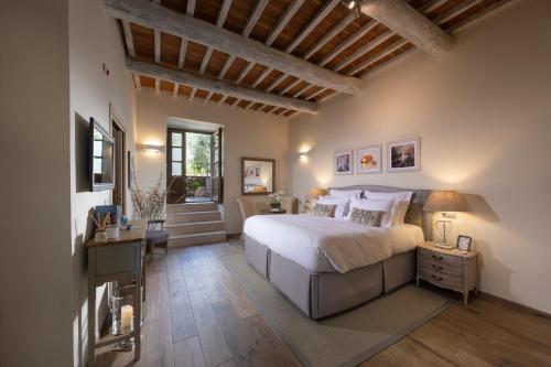 a bedroom with a bed and a desk and a window at Borgo Argiano in Castelnuovo Berardenga