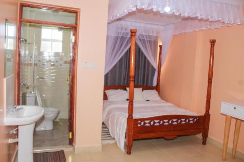 a bedroom with a canopy bed and a bathroom at Royal Palms Executive 2& 1 bedrooms BNB Wote town in Wote