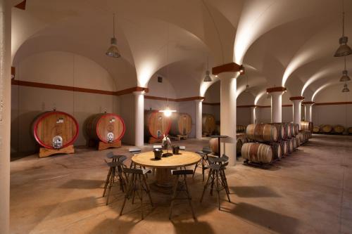 a room with a table and chairs and wine barrels at Borgo Argiano in Castelnuovo Berardenga