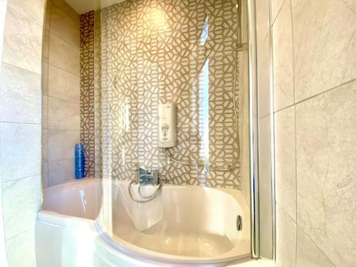 a bathroom with a bath tub with a glass wall at Spacious 3 Bedroom House - 5 Minutes to the nearest Beach! - Great Location - Garden - Parking - Fast WiFi - Smart TV - Newly decorated - sleeps up to 7! Close to Poole & Bournemouth & Sandbanks in Lytchett Minster