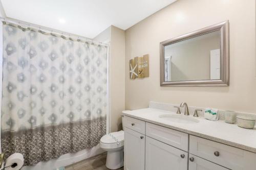 Un baño con lavabo, inodoro y espejo. en Waterfront home with spectacular view, pool and spa, en Marco Island